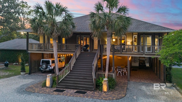 view of front of home featuring roof with shingles, a carport, driveway, and stairway