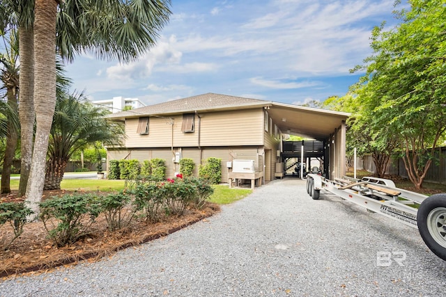 view of front of property featuring fence, driveway, roof with shingles, and a carport