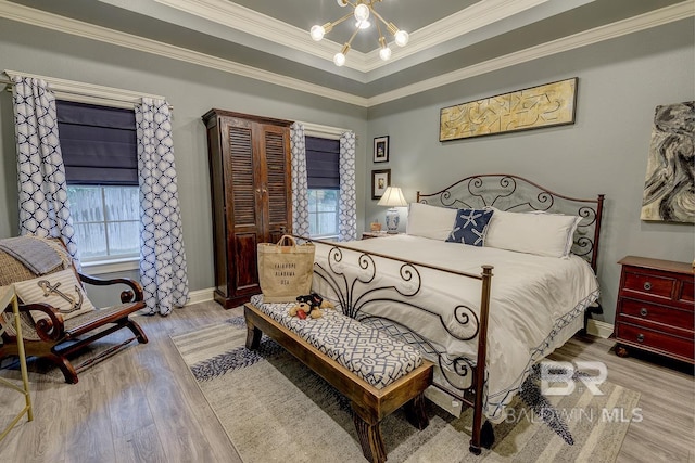 bedroom featuring wood-type flooring, crown molding, a raised ceiling, and multiple windows