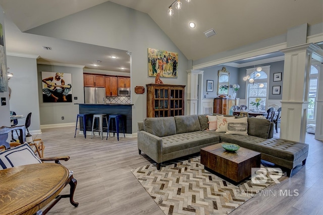 living room with light hardwood / wood-style floors, crown molding, ornate columns, and vaulted ceiling