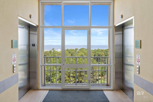 entryway featuring a water view, elevator, and a wealth of natural light