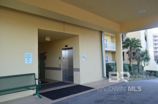 property entrance featuring stucco siding and elevator