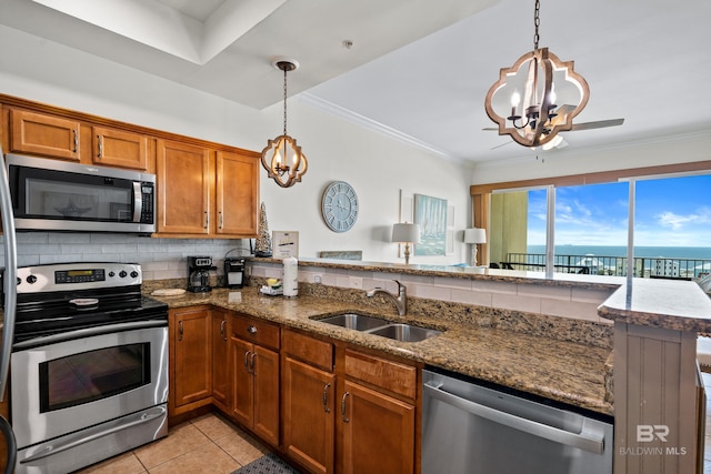 kitchen with brown cabinets, stainless steel appliances, a notable chandelier, and a sink