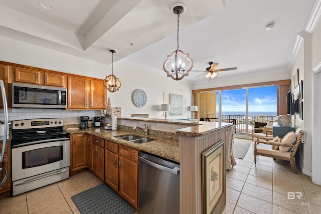 kitchen featuring brown cabinetry, backsplash, appliances with stainless steel finishes, a sink, and a peninsula