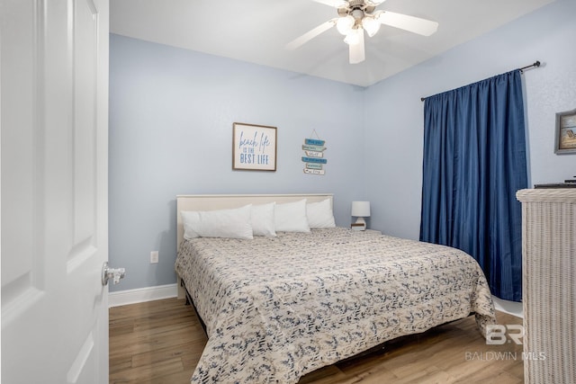 bedroom featuring wood finished floors, a ceiling fan, and baseboards