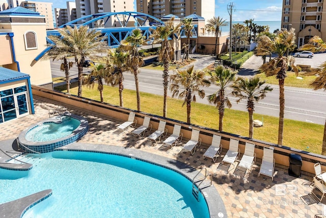 community pool featuring a view of city, a community hot tub, and a patio