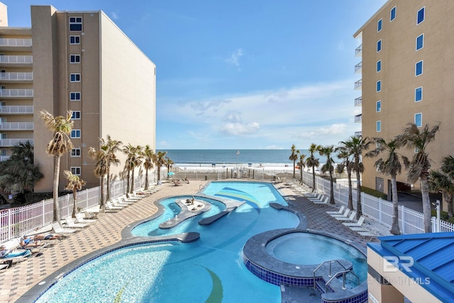 pool with a water view, a patio area, fence, and a community hot tub