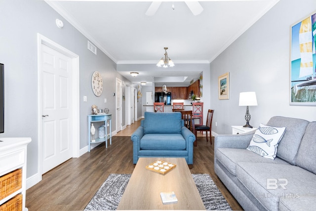 living room featuring baseboards, crown molding, visible vents, and wood finished floors