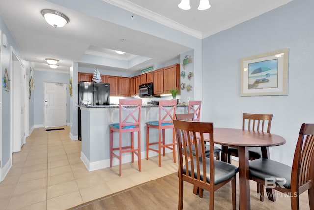 dining space featuring light tile patterned floors, baseboards, a raised ceiling, and crown molding