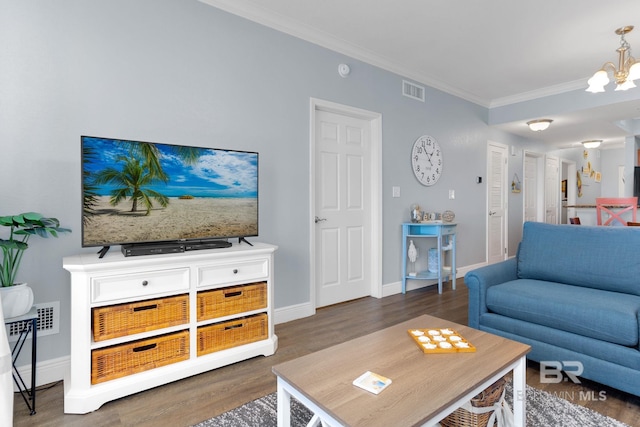 living area with visible vents, an inviting chandelier, ornamental molding, wood finished floors, and baseboards