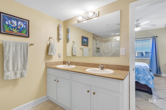 ensuite bathroom with double vanity, tile patterned flooring, a tile shower, and a sink