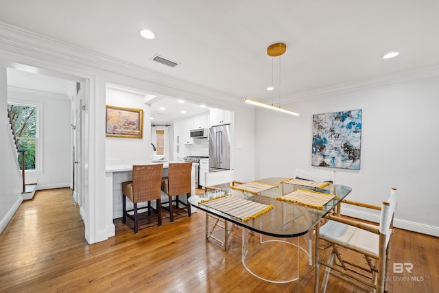 dining room featuring light wood-type flooring, baseboards, crown molding, recessed lighting, and baseboard heating