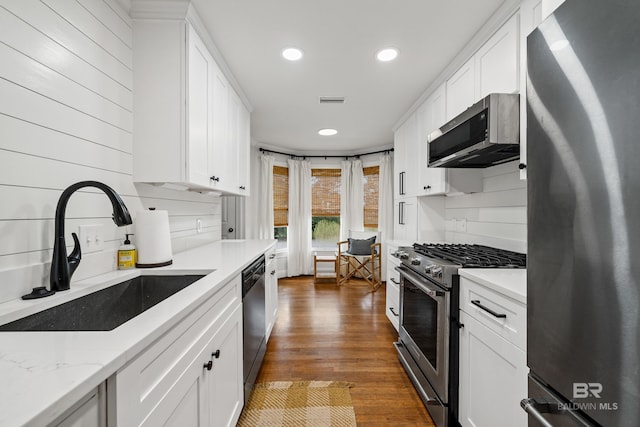 kitchen featuring stainless steel appliances, a sink, recessed lighting, white cabinets, and dark wood-style flooring