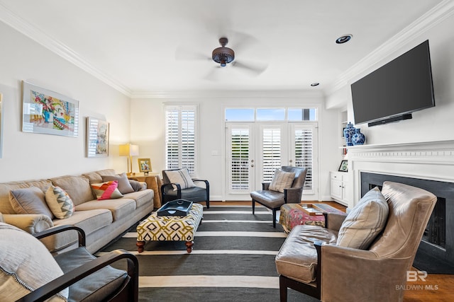 living area with ornamental molding, a ceiling fan, and a fireplace