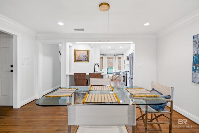 dining space with wood finished floors, crown molding, baseboards, and recessed lighting