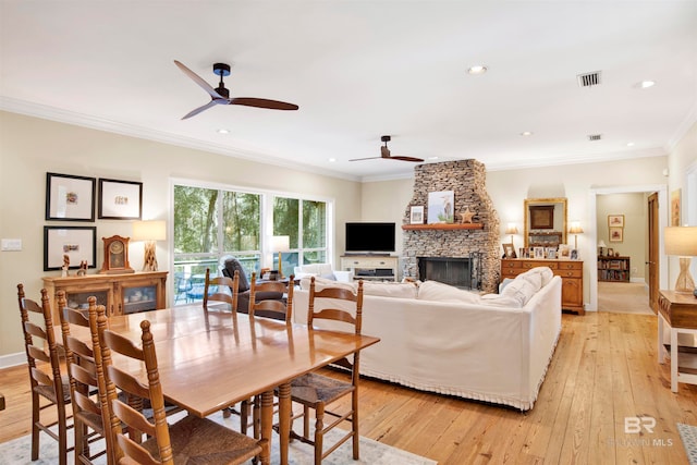 dining area with a fireplace, light hardwood / wood-style floors, and ornamental molding