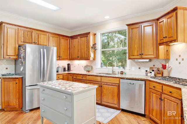 kitchen featuring decorative backsplash, appliances with stainless steel finishes, ornamental molding, sink, and light hardwood / wood-style floors