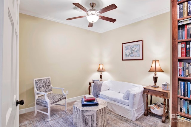 sitting room featuring ceiling fan, carpet floors, and crown molding