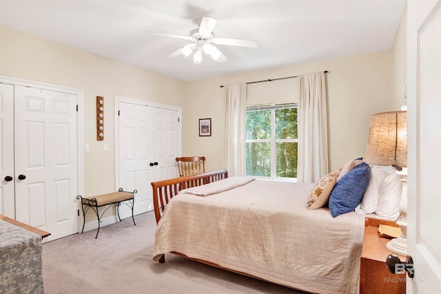 carpeted bedroom featuring ceiling fan and multiple closets