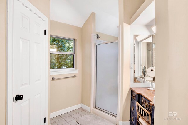 bathroom with a shower with door, vanity, and tile patterned flooring