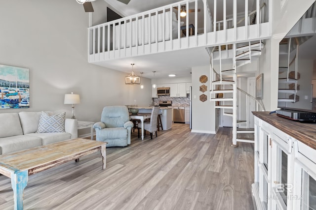 living room featuring a high ceiling, light hardwood / wood-style floors, and ceiling fan