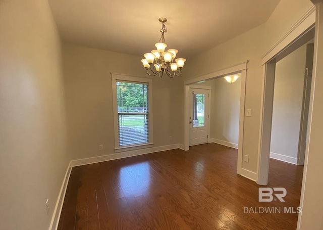 empty room with dark hardwood / wood-style floors and a chandelier