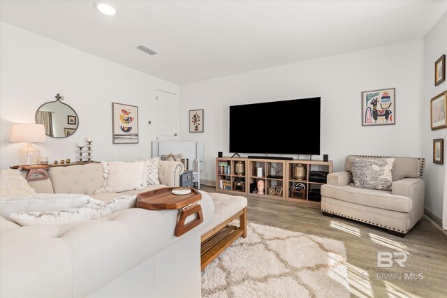 living area with baseboards, visible vents, wood finished floors, and recessed lighting