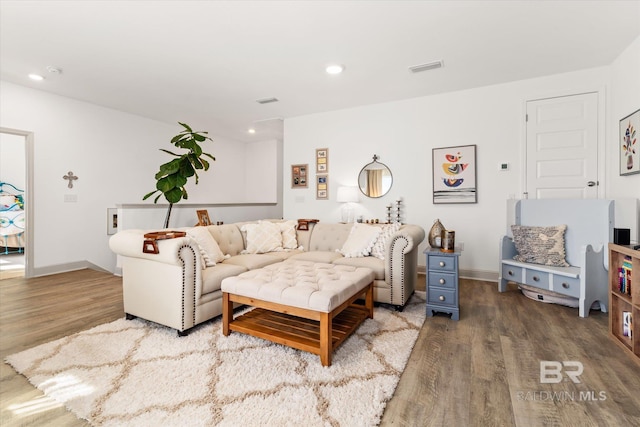 living room with baseboards, visible vents, wood finished floors, and recessed lighting