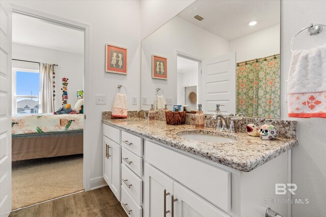 full bathroom with ensuite bathroom, double vanity, wood finished floors, and a sink