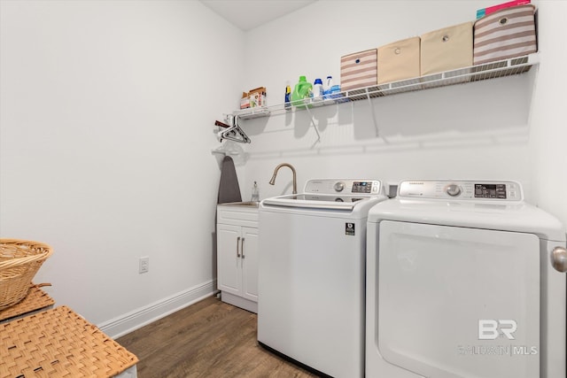 laundry area with washing machine and clothes dryer, cabinet space, a sink, wood finished floors, and baseboards