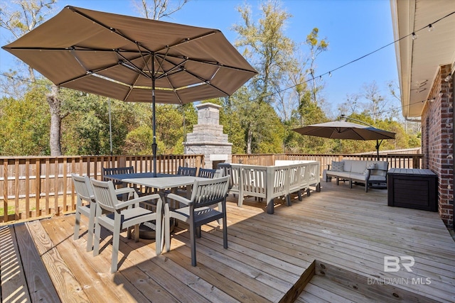 deck with outdoor dining space and an outdoor living space with a fireplace