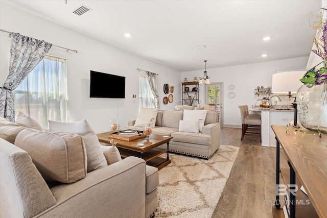 living area with light wood-style floors, visible vents, and recessed lighting