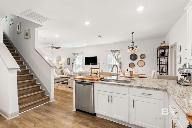 kitchen with visible vents, stainless steel dishwasher, white cabinetry, a sink, and wood finished floors