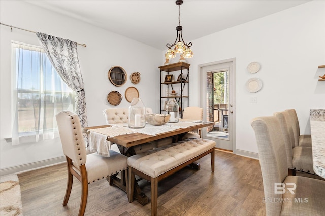 dining space featuring an inviting chandelier, wood finished floors, and baseboards