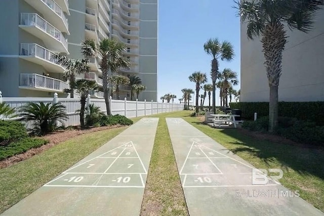 view of property's community with fence and shuffleboard