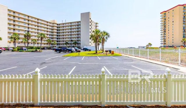 uncovered parking lot with a view of city and fence