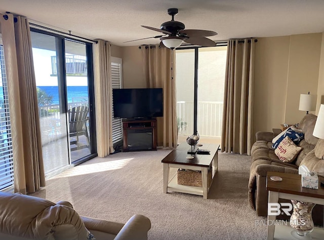 living room featuring light carpet, ceiling fan, expansive windows, and a textured ceiling