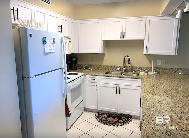 kitchen featuring light stone counters, visible vents, white cabinetry, a sink, and white appliances