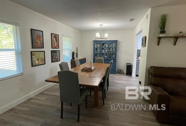 dining space with hardwood / wood-style flooring and a notable chandelier