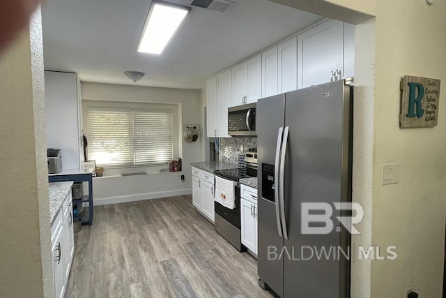 kitchen featuring light hardwood / wood-style flooring, decorative backsplash, light stone countertops, white cabinetry, and stainless steel appliances