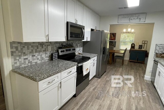 kitchen featuring pendant lighting, white cabinetry, stainless steel appliances, and stone counters