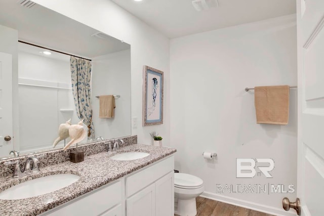 bathroom with hardwood / wood-style floors, vanity, toilet, and curtained shower