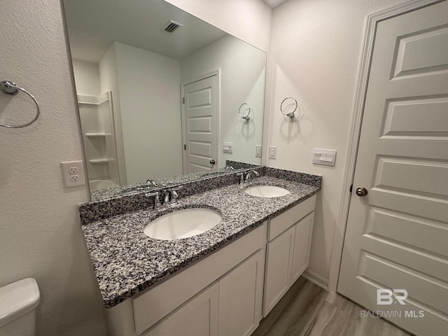 bathroom featuring toilet, vanity, and hardwood / wood-style flooring