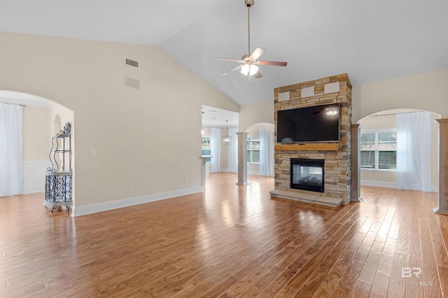 unfurnished living room featuring hardwood / wood-style flooring, a stone fireplace, high vaulted ceiling, and ceiling fan