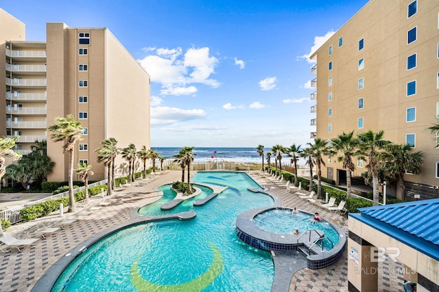 view of swimming pool featuring a patio, a community hot tub, and a water view