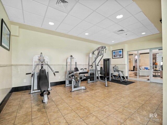 exercise room with a paneled ceiling and light tile patterned floors