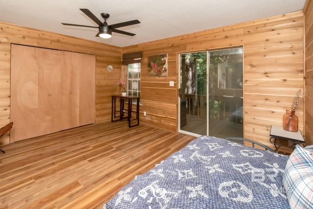 bedroom featuring ceiling fan, access to exterior, light hardwood / wood-style floors, and multiple windows