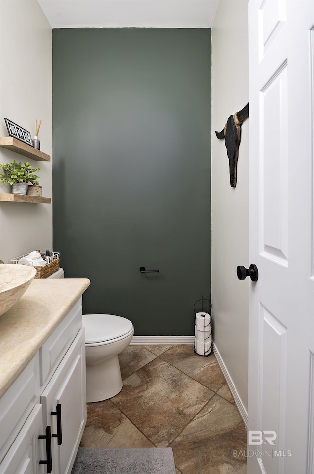 bathroom with vanity, toilet, and baseboards