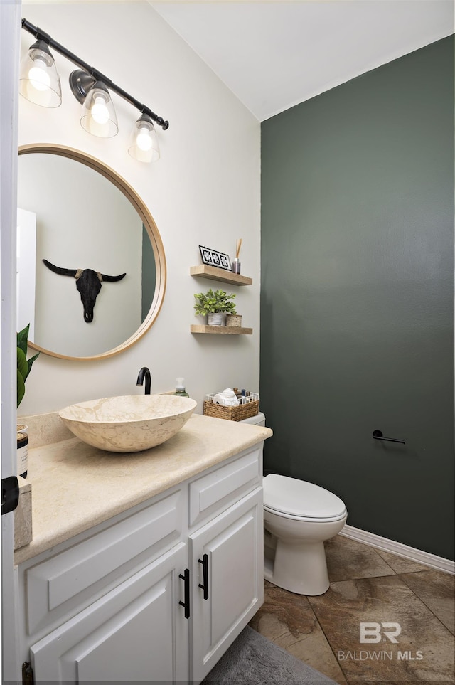 bathroom featuring vanity, toilet, and baseboards