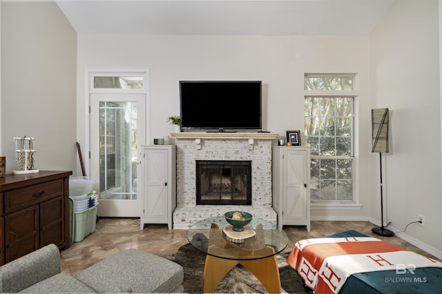 living room with a brick fireplace and baseboards